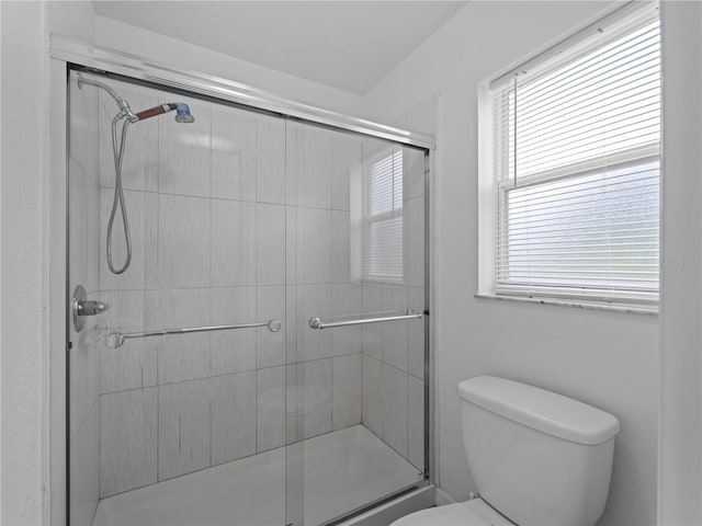 bathroom featuring a shower with shower door and toilet