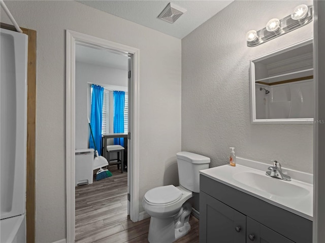 bathroom with wood-type flooring, vanity, toilet, and a textured ceiling