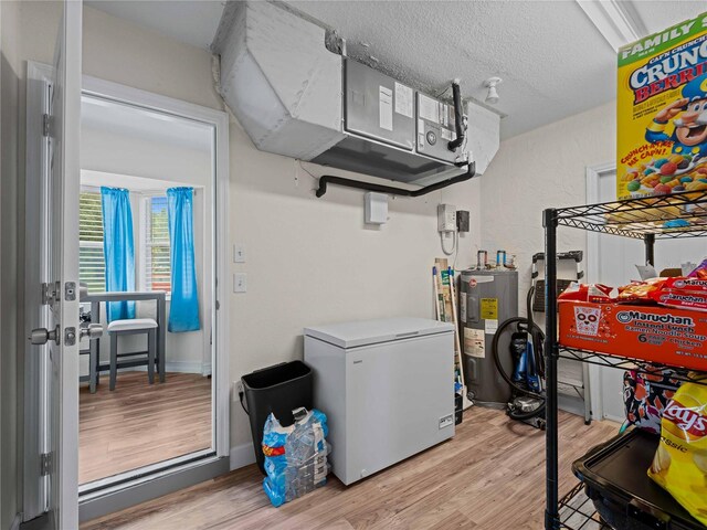 laundry room with electric water heater, a textured ceiling, and light hardwood / wood-style floors