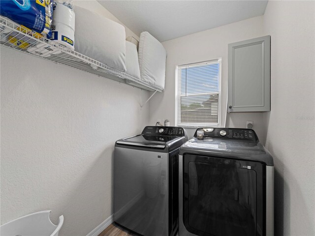 laundry room featuring cabinets, hardwood / wood-style flooring, and washing machine and clothes dryer