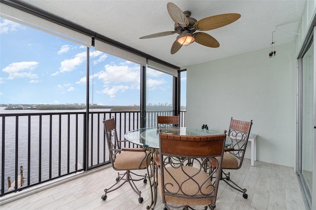 sunroom featuring a water view and ceiling fan