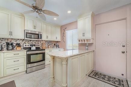 kitchen with ceiling fan, stainless steel appliances, decorative backsplash, and cream cabinetry