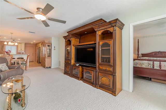 carpeted living room with a textured ceiling and ceiling fan with notable chandelier