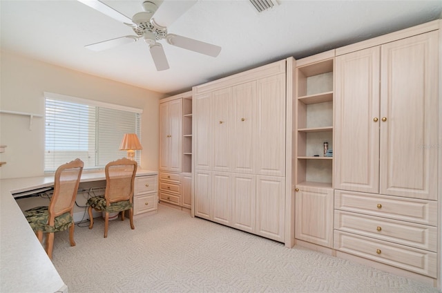 office space featuring built in desk, light carpet, and ceiling fan