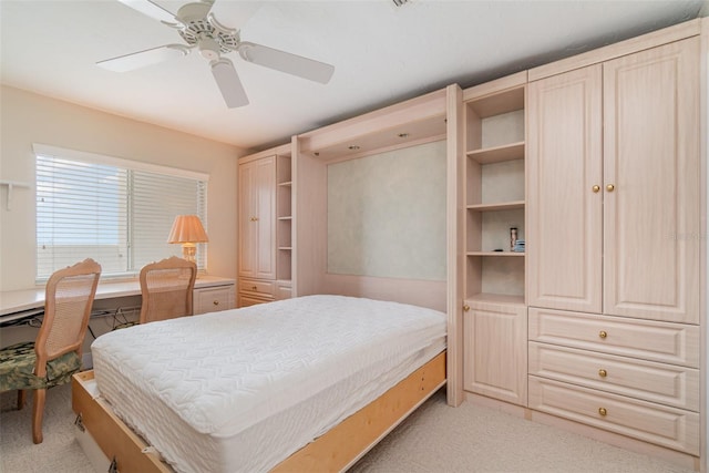 bedroom with built in desk, ceiling fan, and light carpet