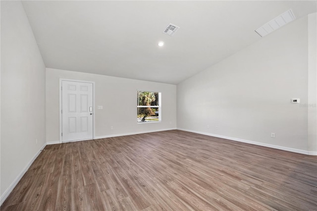 spare room featuring hardwood / wood-style flooring and lofted ceiling