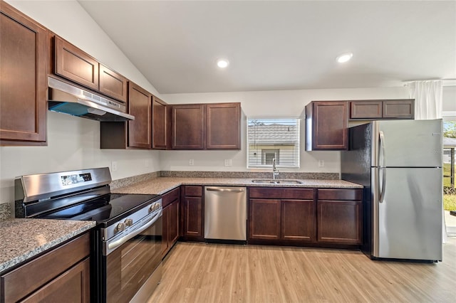 kitchen with appliances with stainless steel finishes, sink, dark brown cabinets, light hardwood / wood-style floors, and vaulted ceiling