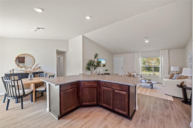 kitchen with vaulted ceiling, an island with sink, and light hardwood / wood-style floors