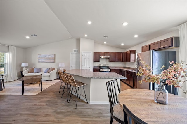 kitchen featuring appliances with stainless steel finishes, lofted ceiling, a center island, and light wood-type flooring