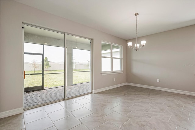 tiled empty room with a healthy amount of sunlight and an inviting chandelier