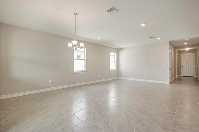 tiled spare room with a chandelier