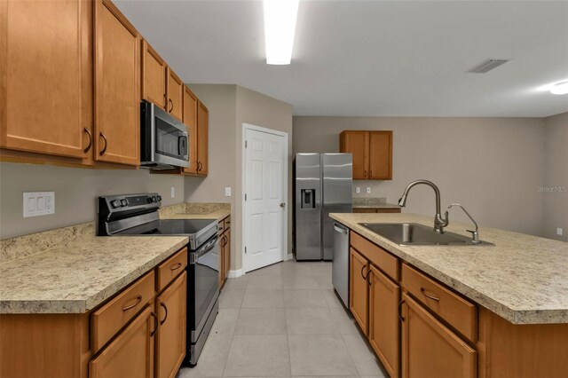 kitchen featuring light tile patterned floors, appliances with stainless steel finishes, sink, and a center island with sink