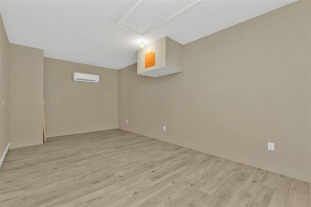 unfurnished room with light hardwood / wood-style floors and a wall unit AC