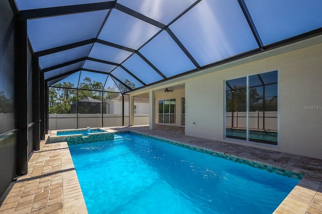 view of pool with an in ground hot tub, a patio area, glass enclosure, and ceiling fan