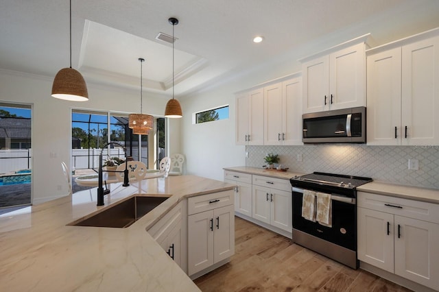 kitchen featuring white cabinetry, light stone countertops, appliances with stainless steel finishes, and pendant lighting