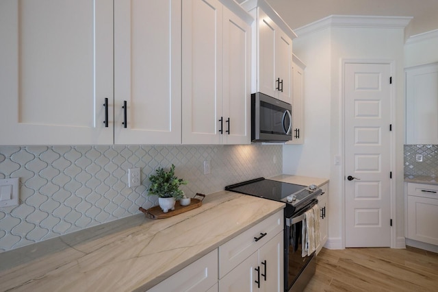 kitchen with tasteful backsplash, light stone countertops, appliances with stainless steel finishes, light wood-type flooring, and white cabinetry