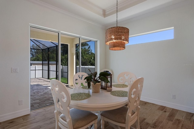 dining room featuring a wealth of natural light, crown molding, a tray ceiling, and light hardwood / wood-style floors