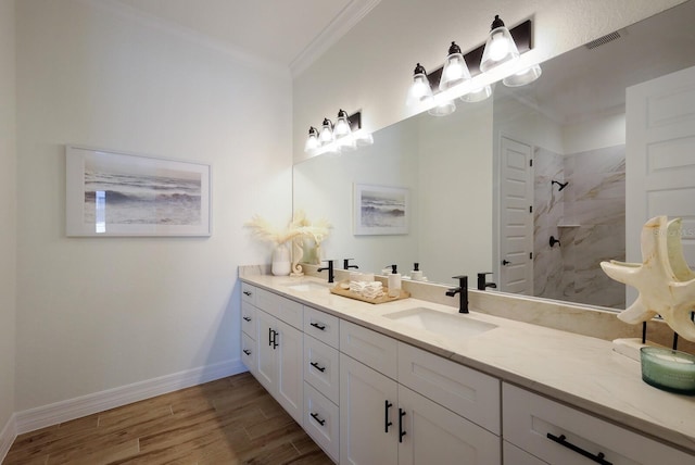 bathroom featuring a tile shower, wood-type flooring, ornamental molding, and vanity