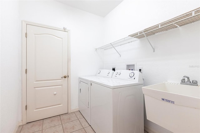 laundry area featuring washer and clothes dryer, sink, and light tile patterned floors