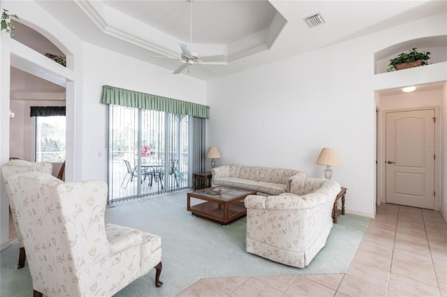 living room featuring light tile patterned floors, a tray ceiling, and ceiling fan