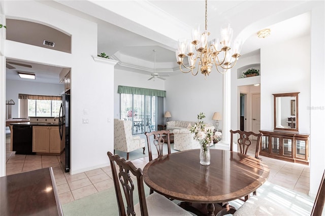 dining area with a tray ceiling, light tile patterned floors, and ceiling fan with notable chandelier