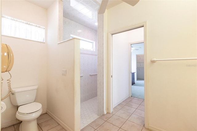 bathroom featuring tile patterned flooring, a tile shower, ceiling fan, and toilet