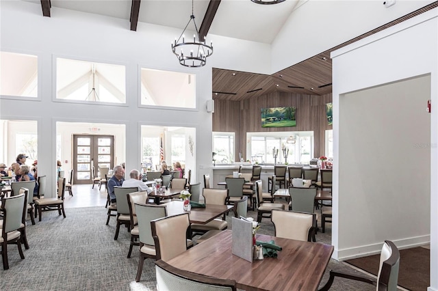 dining space featuring beamed ceiling, a chandelier, high vaulted ceiling, and french doors