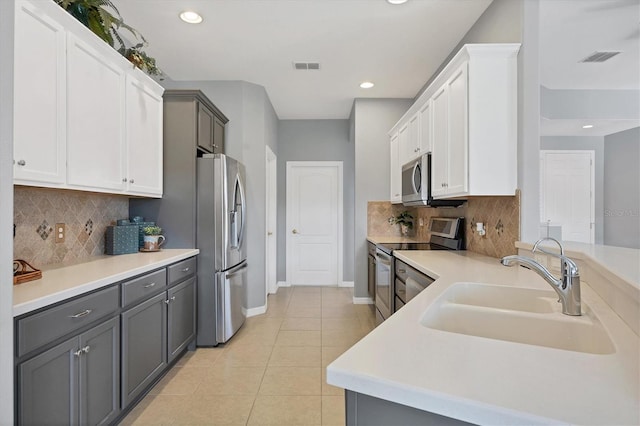 kitchen featuring gray cabinetry, appliances with stainless steel finishes, sink, and white cabinetry