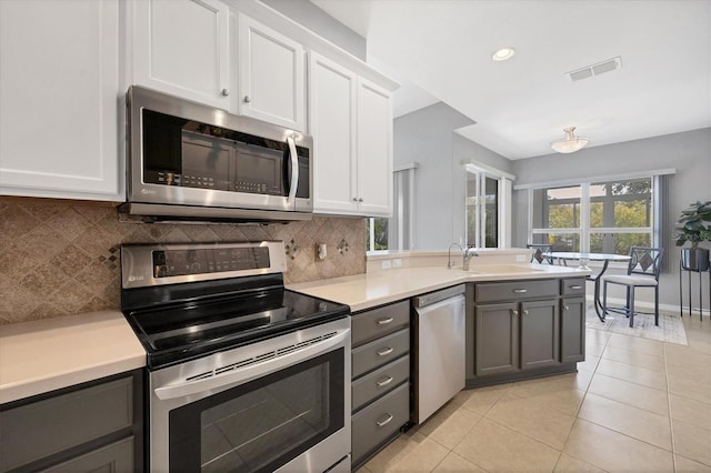 kitchen with gray cabinetry, stainless steel appliances, decorative backsplash, and white cabinets