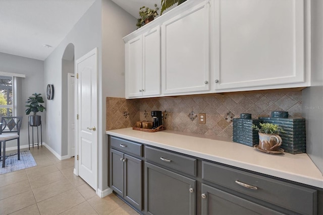 kitchen featuring white cabinets, tasteful backsplash, light tile patterned floors, and gray cabinetry