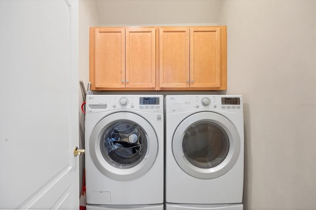 washroom featuring separate washer and dryer and cabinets