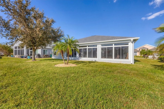 rear view of property featuring a sunroom and a lawn