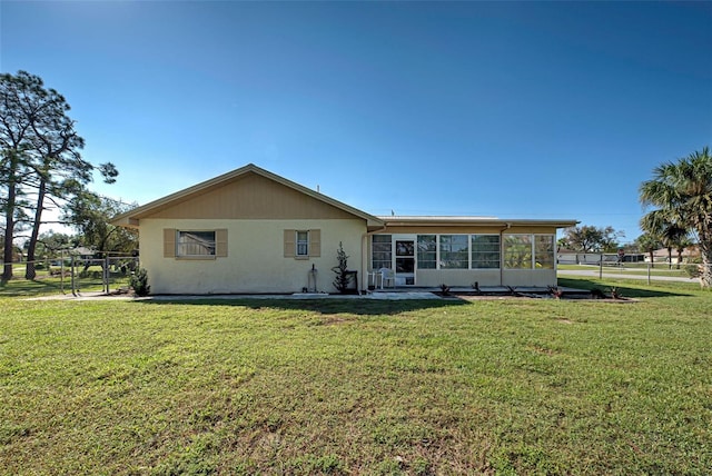 rear view of house with a yard and a sunroom