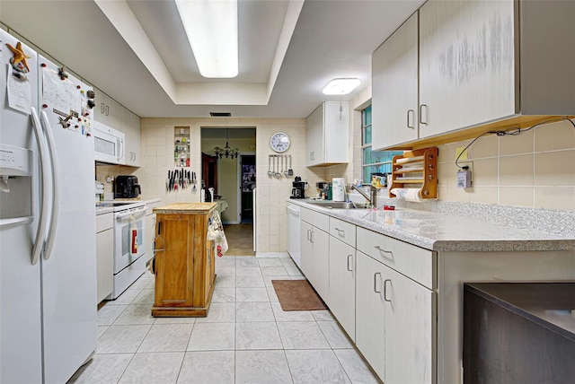 kitchen with white appliances, tasteful backsplash, sink, and white cabinets