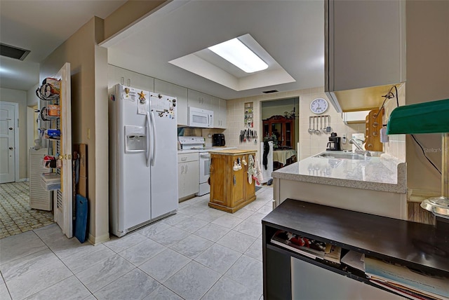 kitchen featuring white appliances, sink, white cabinets, decorative backsplash, and light tile patterned floors