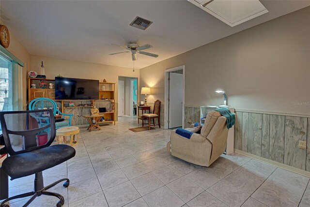 tiled living room featuring wooden walls and ceiling fan