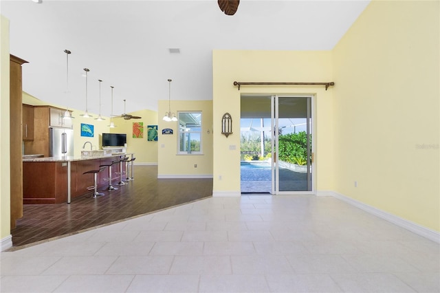 unfurnished living room featuring ceiling fan, light hardwood / wood-style floors, and a towering ceiling