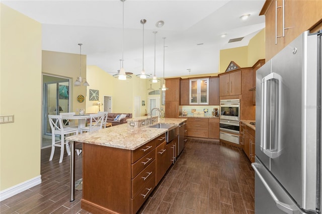 kitchen with sink, hanging light fixtures, stainless steel appliances, dark hardwood / wood-style floors, and a kitchen island with sink