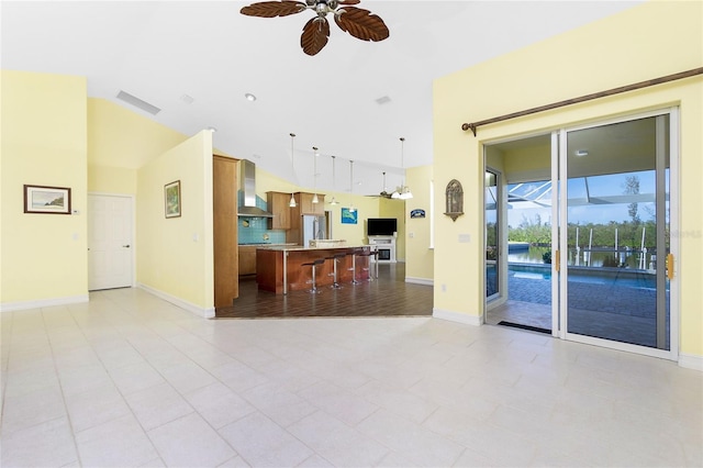 living room with ceiling fan, lofted ceiling, and light tile patterned floors