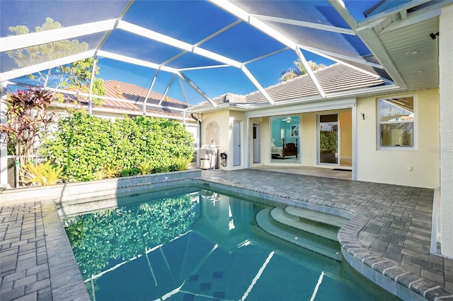 view of pool with glass enclosure, a patio area, and ceiling fan