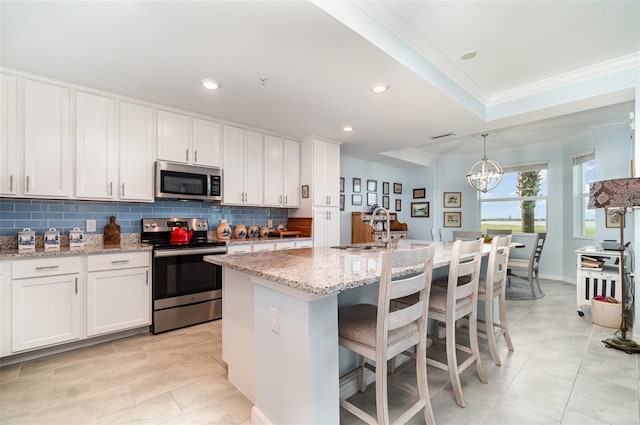 kitchen with a center island with sink, crown molding, appliances with stainless steel finishes, and white cabinetry