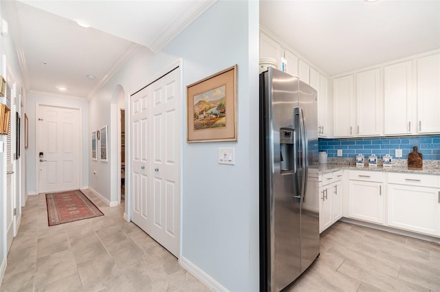 kitchen with white cabinets, light stone countertops, decorative backsplash, and stainless steel fridge