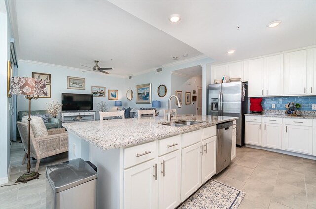 kitchen featuring an island with sink, stainless steel appliances, crown molding, sink, and white cabinetry