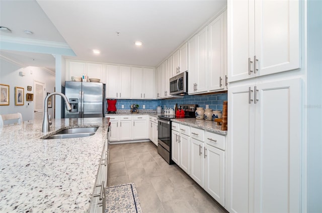 kitchen featuring white cabinetry, light stone countertops, stainless steel appliances, and sink