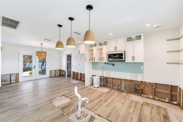 kitchen with white cabinetry, backsplash, light hardwood / wood-style flooring, and hanging light fixtures