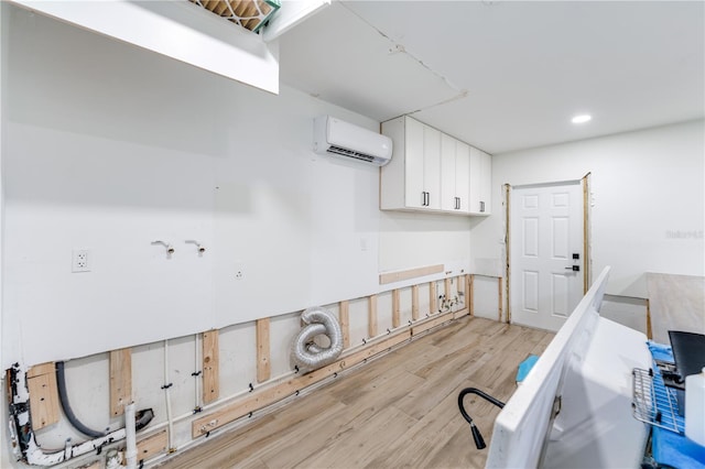 laundry area with a wall unit AC and light hardwood / wood-style floors