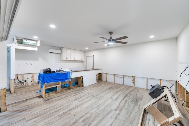 interior space featuring an AC wall unit, light hardwood / wood-style flooring, and ceiling fan