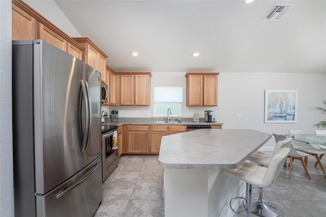 kitchen with light tile patterned floors, a kitchen bar, stainless steel appliances, sink, and a center island