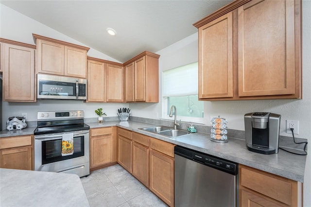 kitchen featuring sink, appliances with stainless steel finishes, light tile patterned floors, and vaulted ceiling