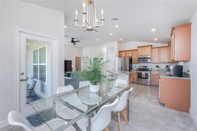 dining room with light tile patterned floors, vaulted ceiling, and ceiling fan with notable chandelier